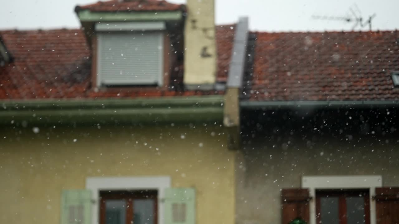 冬天飘落的雪花。雪花以240帧的超慢动作飘落，背景是欧洲建筑的屋顶视频素材