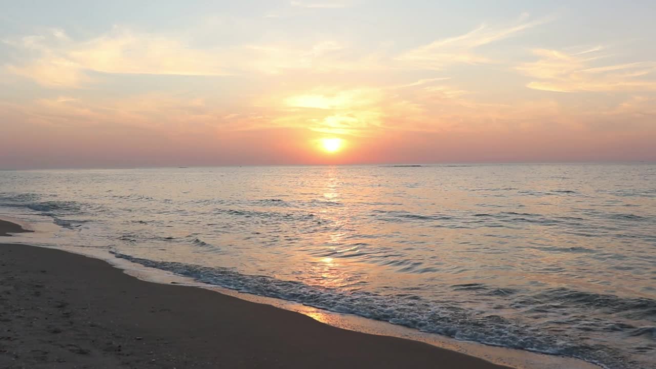 夕阳下的海滩在水面上，海浪的轰鸣声作为背景视频素材