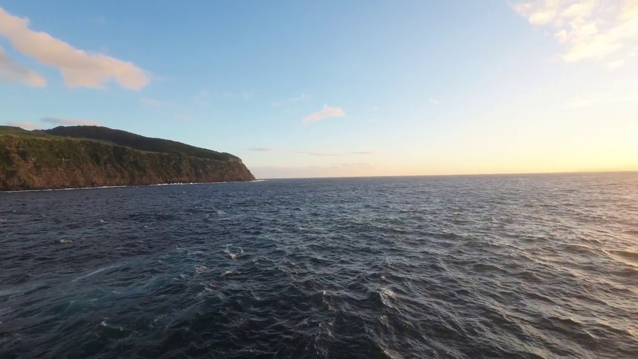 航拍飞行非常近的泡沫浪花海洋撞击岩石海岸由日落岩石视频素材