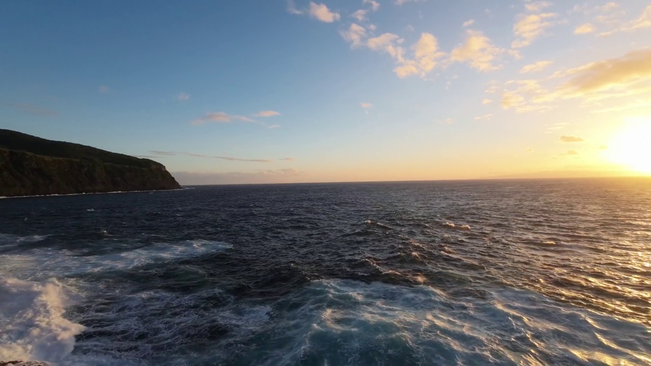 航拍飞行非常近的泡沫浪花海洋撞击岩石海岸由日落岩石视频素材