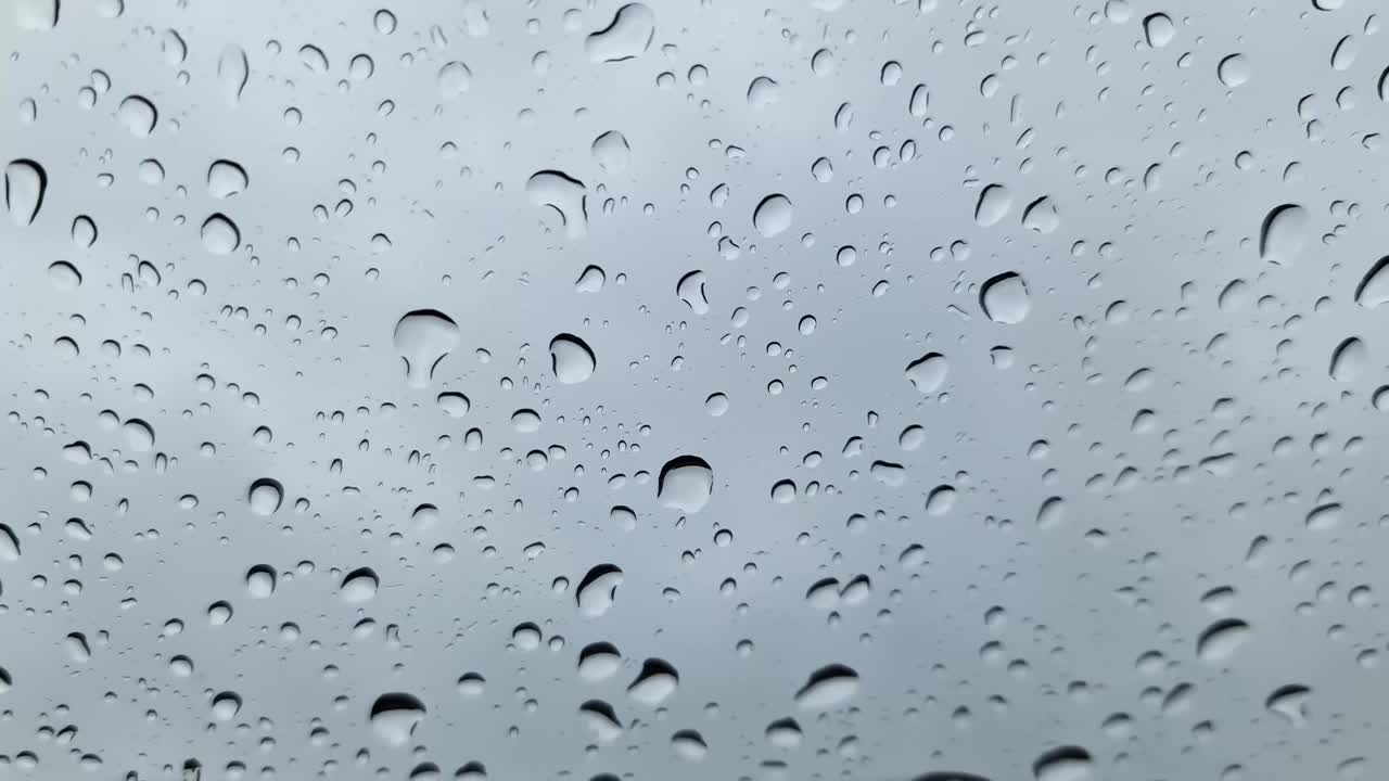 近距离观看，雨滴从车窗上流下。视频素材