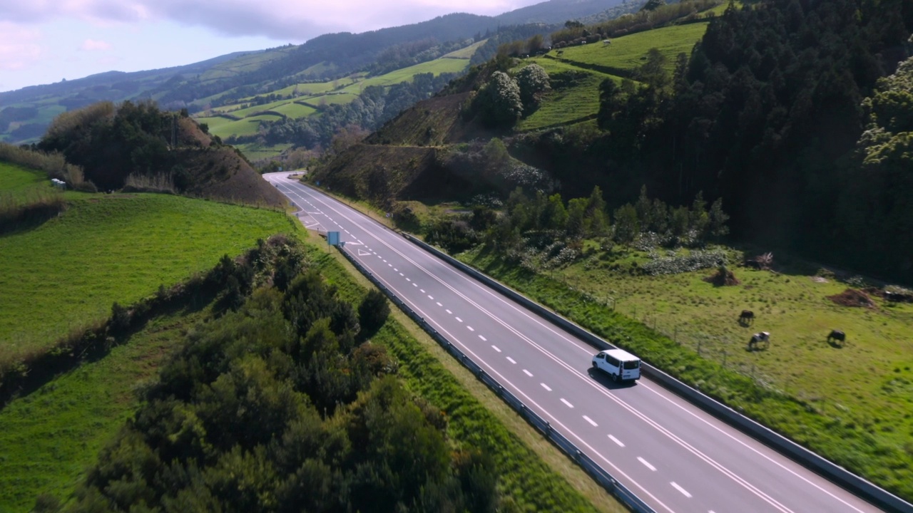 在葡萄牙的Ilha de Sao Miguel，在美丽的山丘和绿色的草地之间的道路景观视频素材