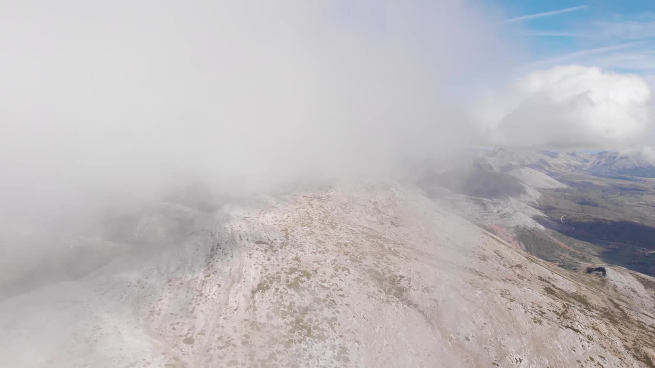 航拍的无人机飞过大片云层，接近一座沙色的山。视频素材