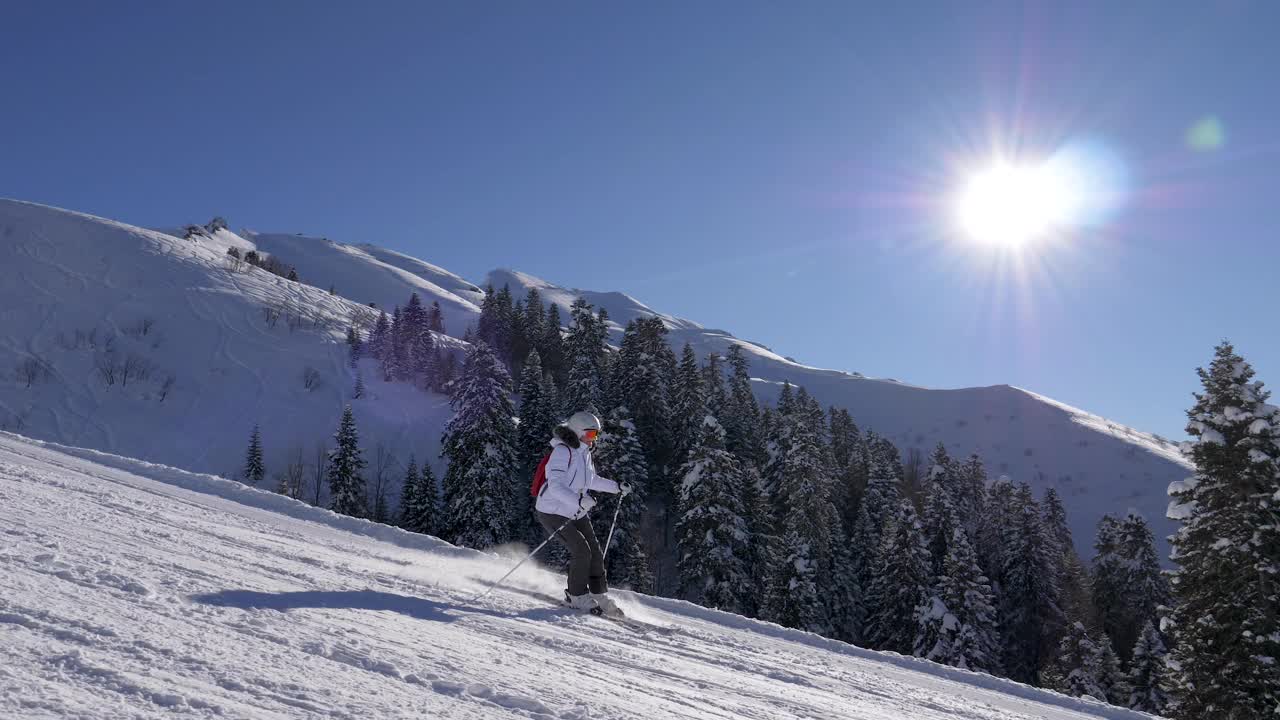 滑雪者在阳光明媚的冬日滑雪场滑雪背景是雪山视频素材