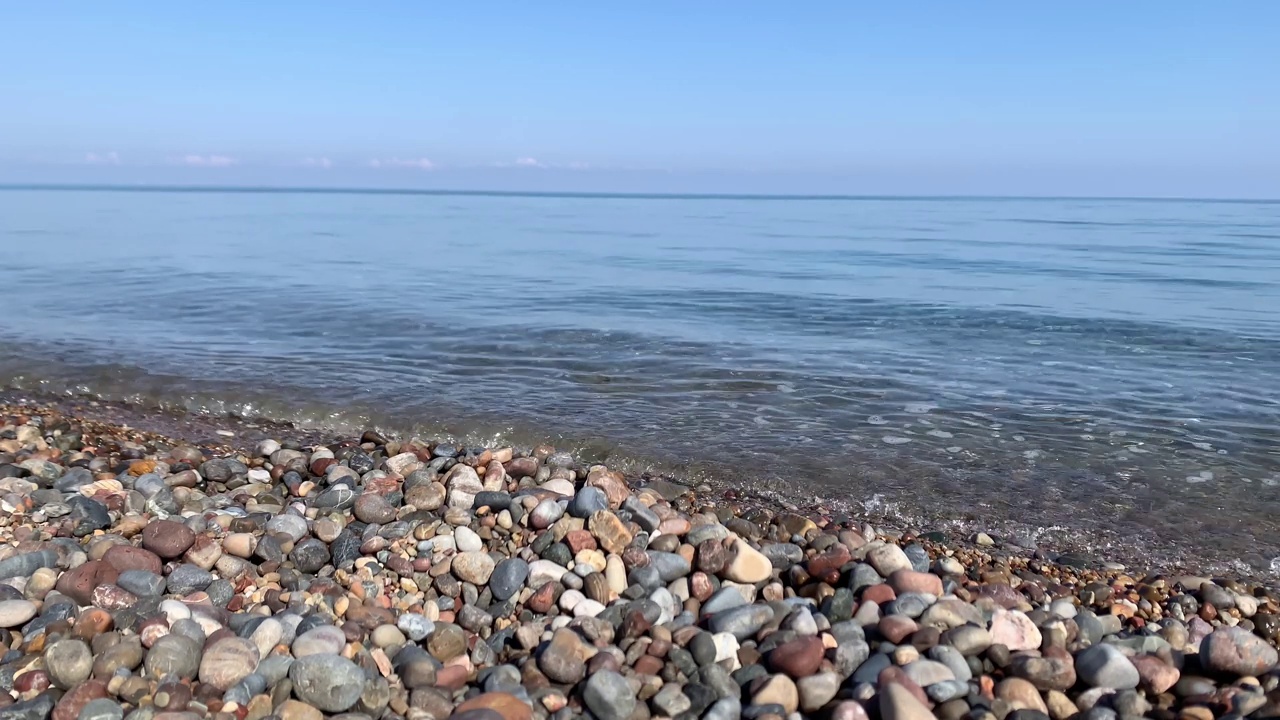 海滩卵石上平静的大海是一个股票视频，包含海浪冲刷海滩卵石的美丽特写镜头。视频素材