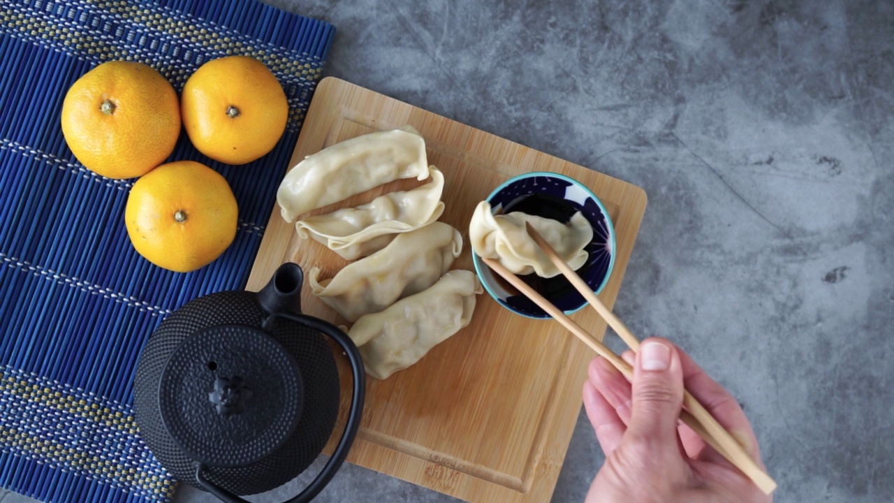 用筷子手吃中餐。装饰用茶壶和橘子在石头背景。视频素材