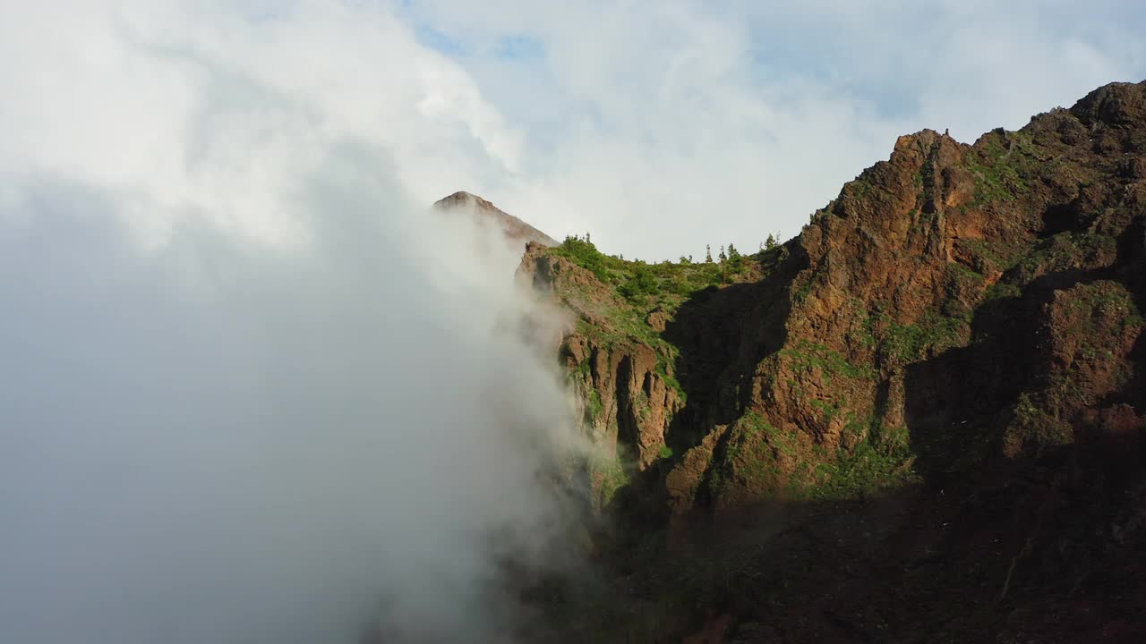 空中飞行:在山顶上穿过雾云的空中飞行雾霾迅速从山腰下到峡谷针叶林。特内里费岛泰德国家公园的晴天。视频素材