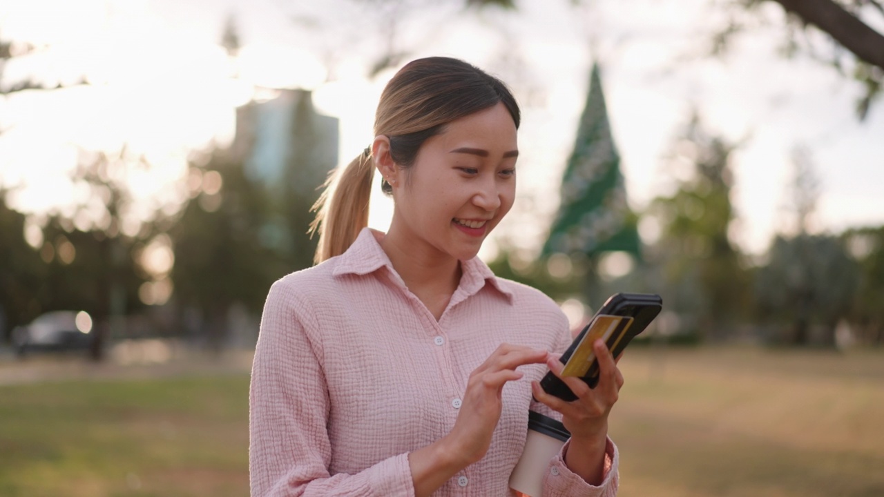 亚洲妇女在公园用电话网上购物视频素材