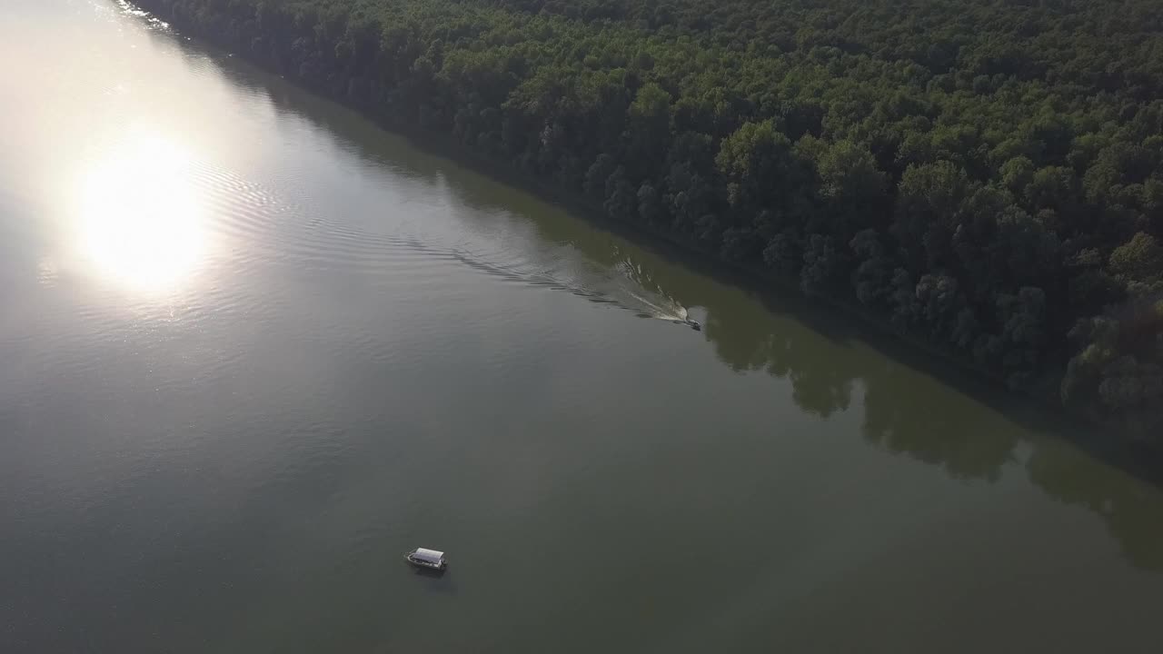 河流的鸟瞰图，有海岸线上的树木和水面上太阳的倒影视频素材