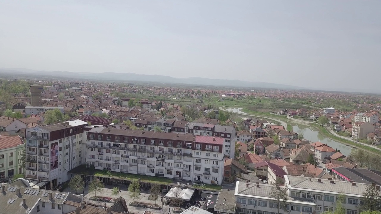 在昏暗的天空下，彩色密集的建筑和交通道路之间的河流鸟瞰图视频素材