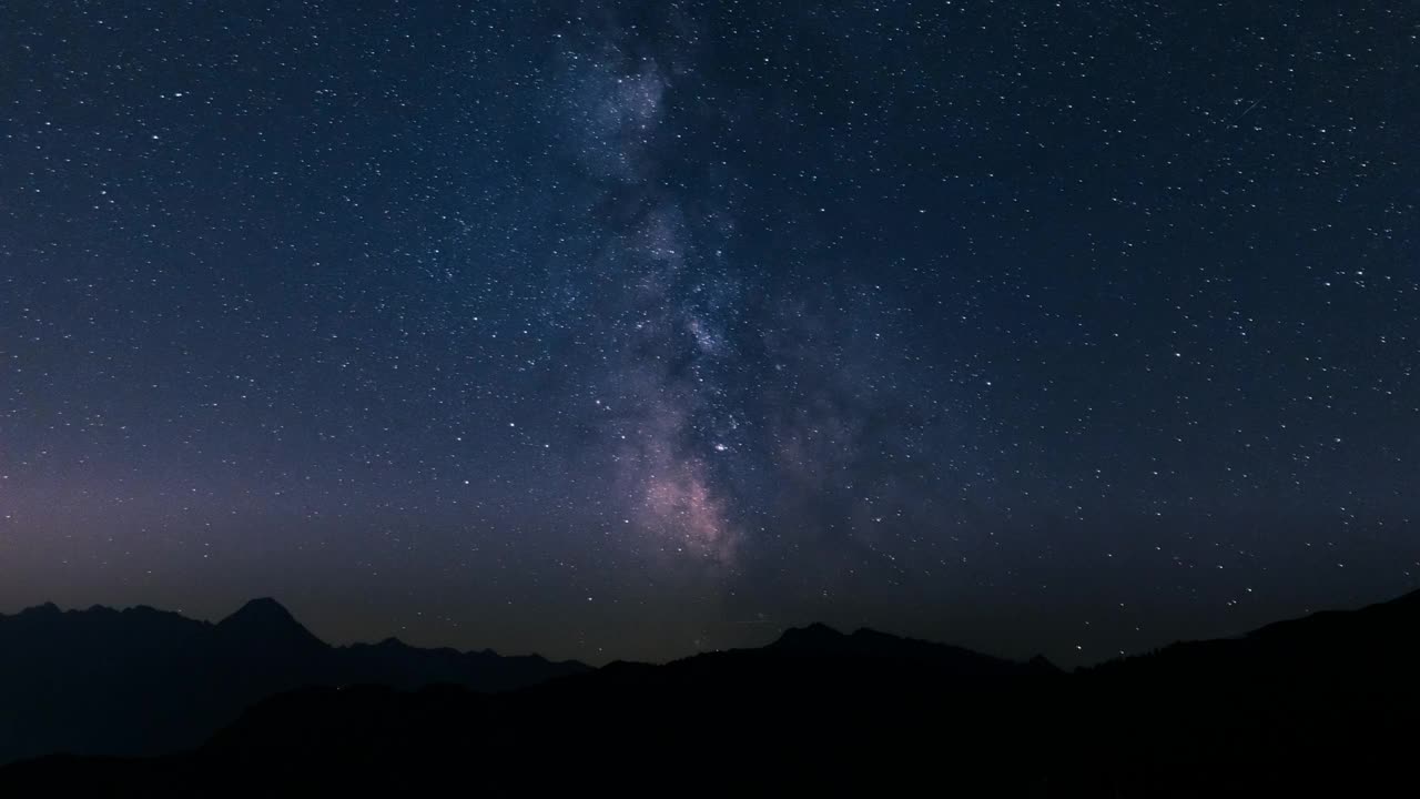 一个星夜的延时镜头，流动的云映衬着山的轮廓视频素材