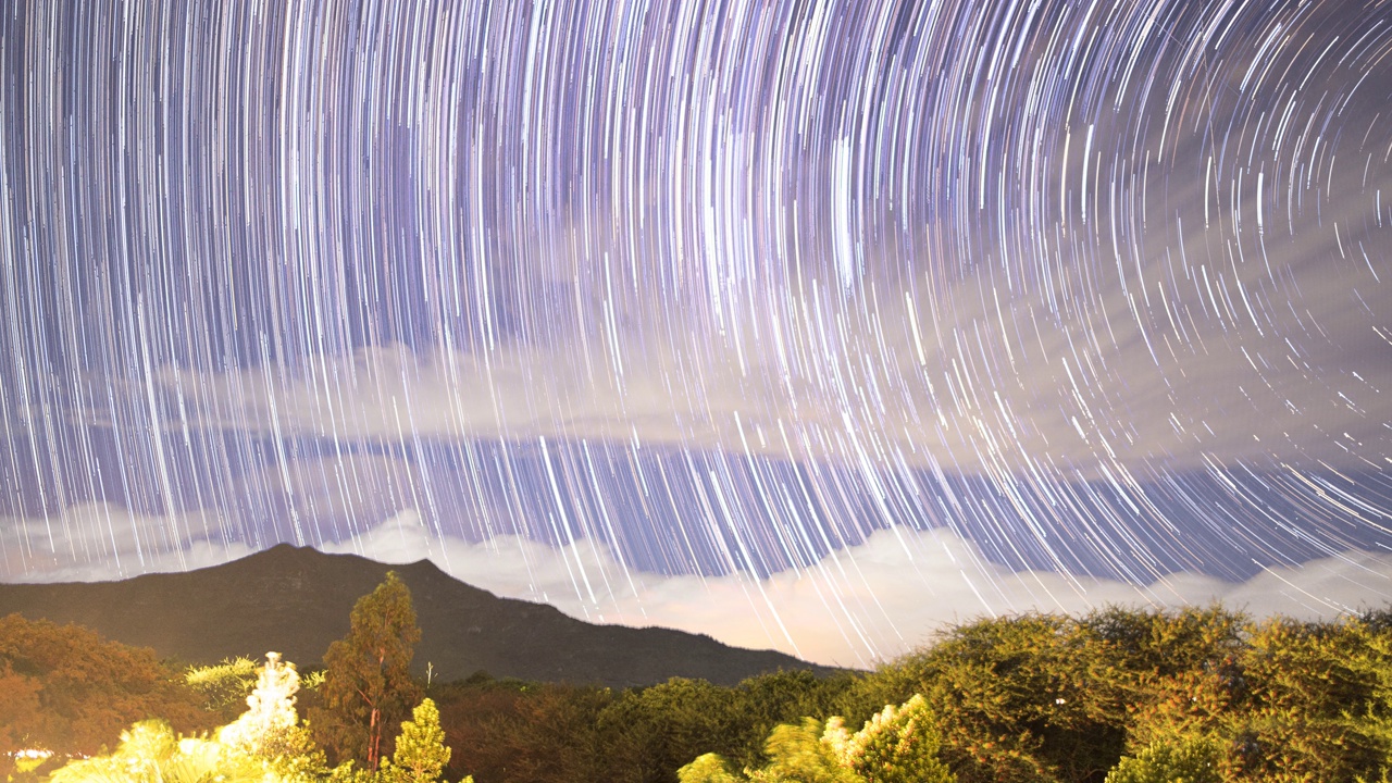 一个星夜的延时镜头，流动的云映衬着山的轮廓视频素材