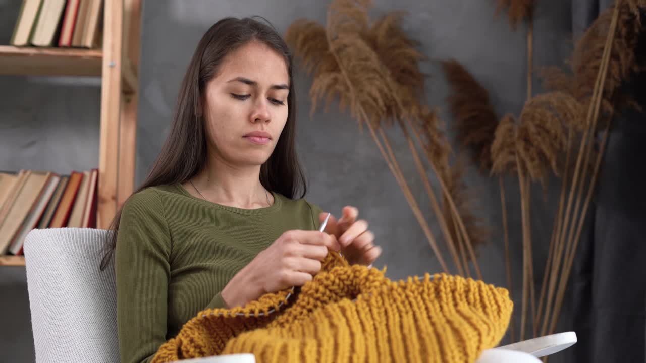 拉丁年轻女子编织保暖毛衣，针织饰品在家里，休闲和爱好视频素材