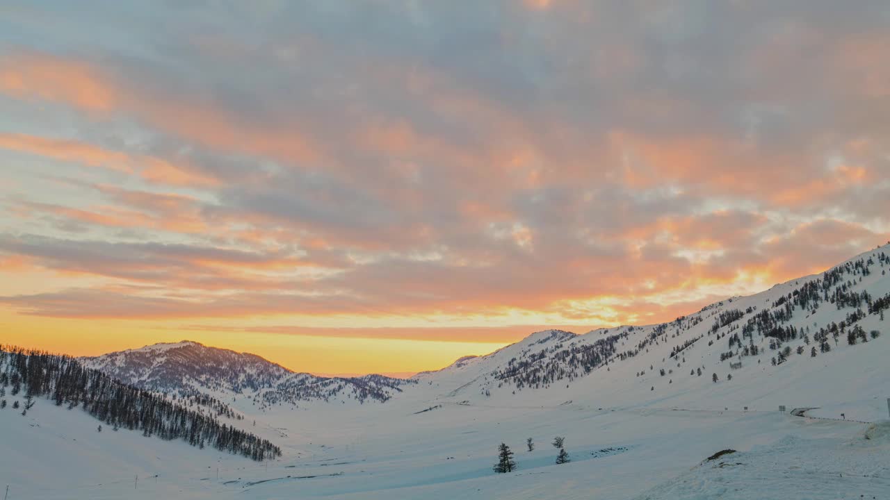 空中延时拍摄的雪覆盖的森林、雪山和日出时的云。视频素材