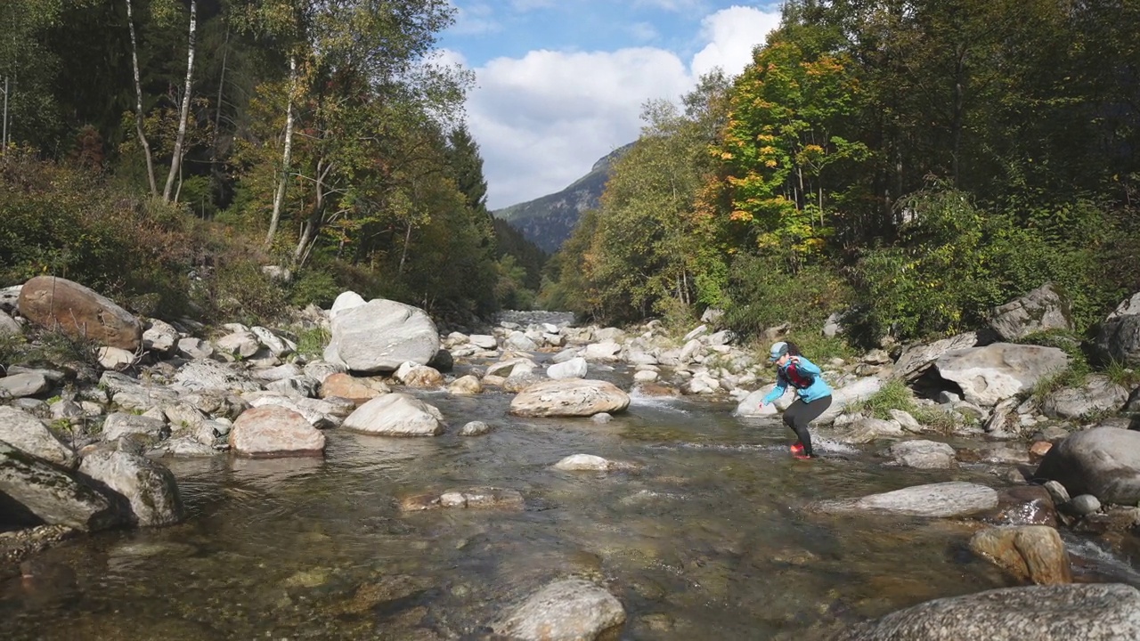 一位女性徒步旅行者穿过河流，水淹到膝盖视频素材