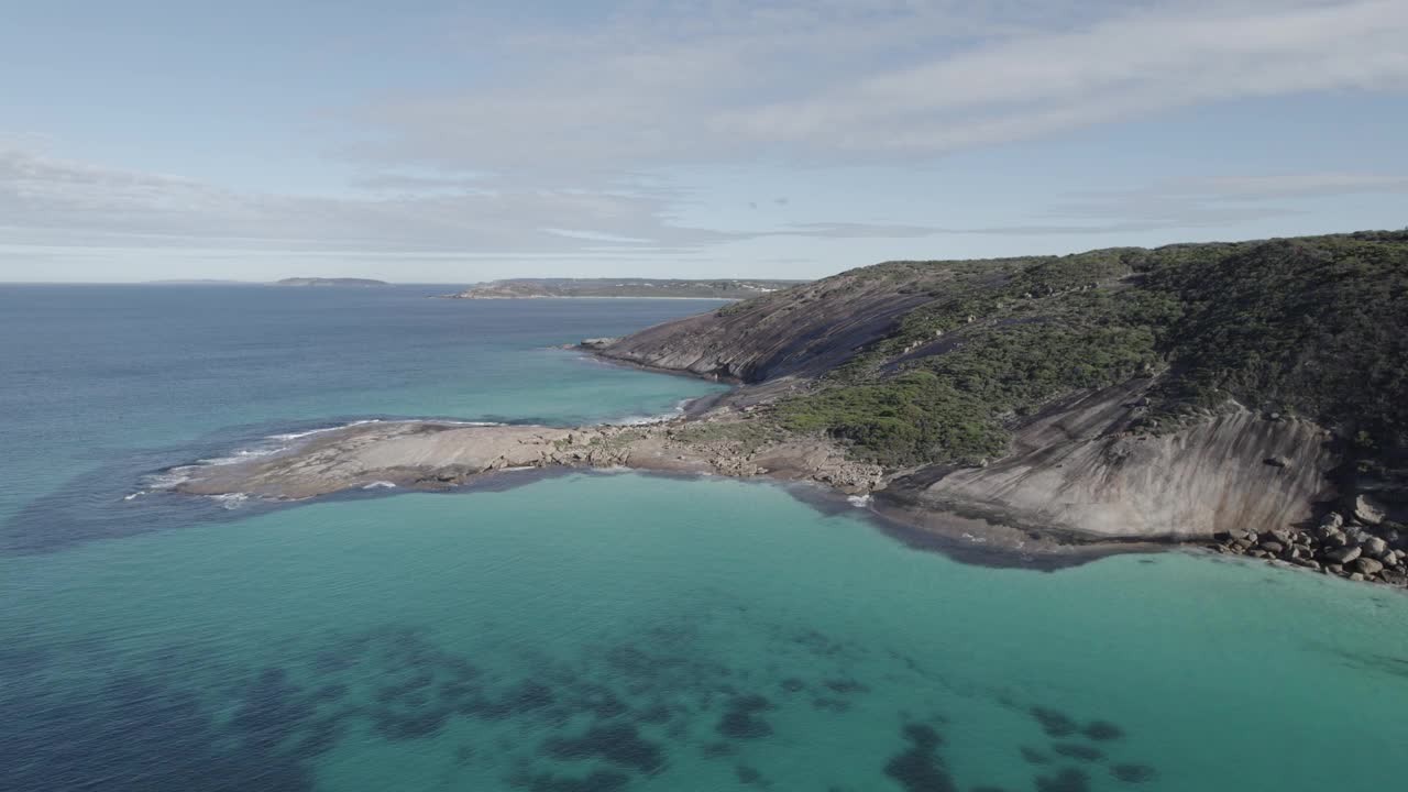 空中拍摄的清晰的海滩海浪冲刷着埃斯佩兰斯森林覆盖的丘陵视频素材