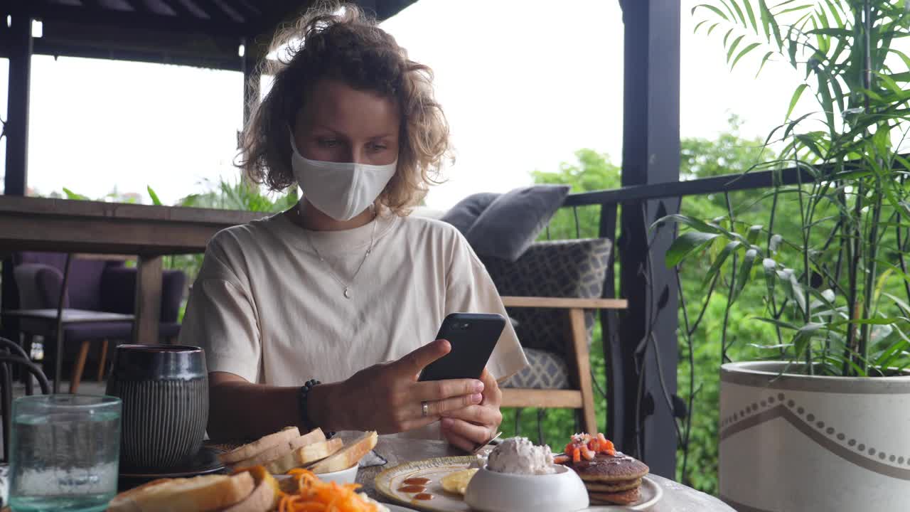 一位白人女性博主在户外餐厅拍摄她的素食午餐。她详细地解释了每道菜的组成。这激发了她的订阅者的兴趣。视频素材