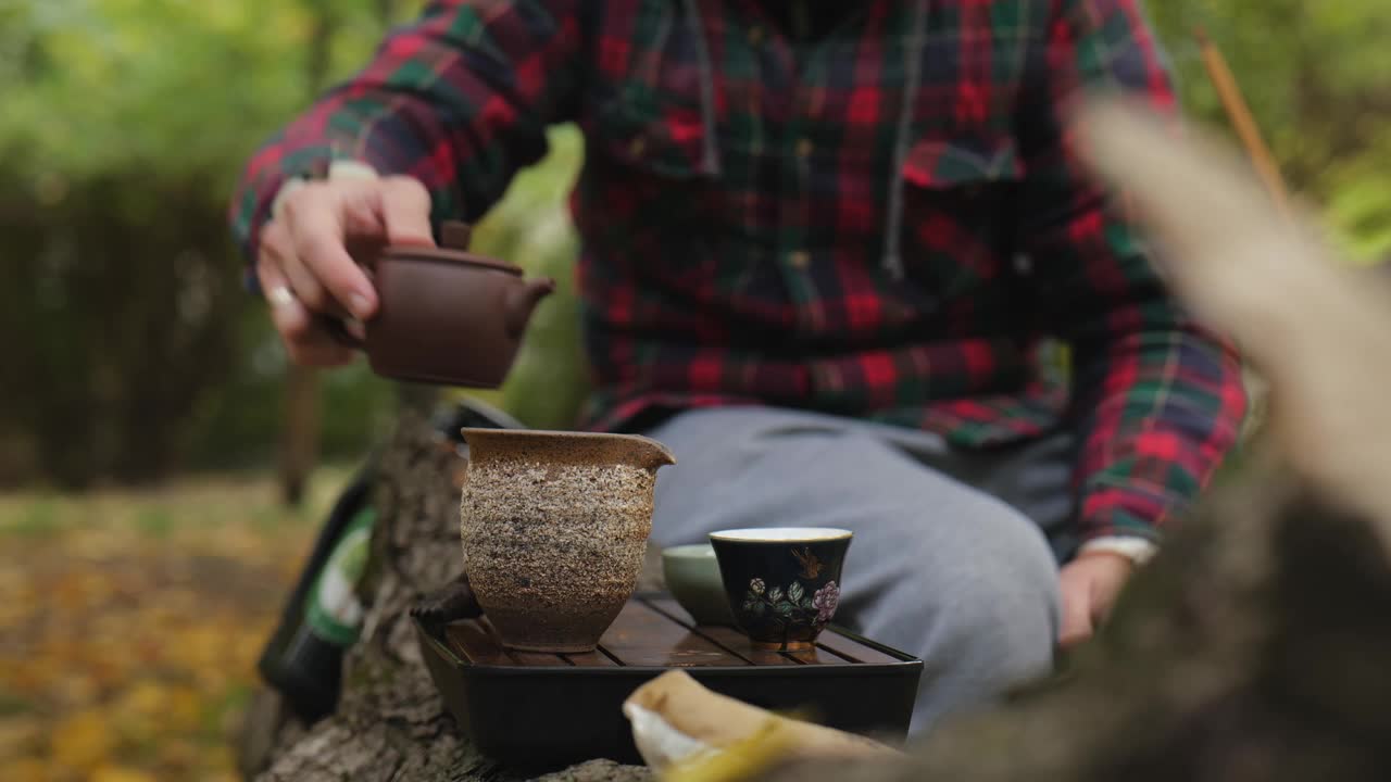 留着胡子的茶师用陶壶倒普洱茶。户外茶道视频素材