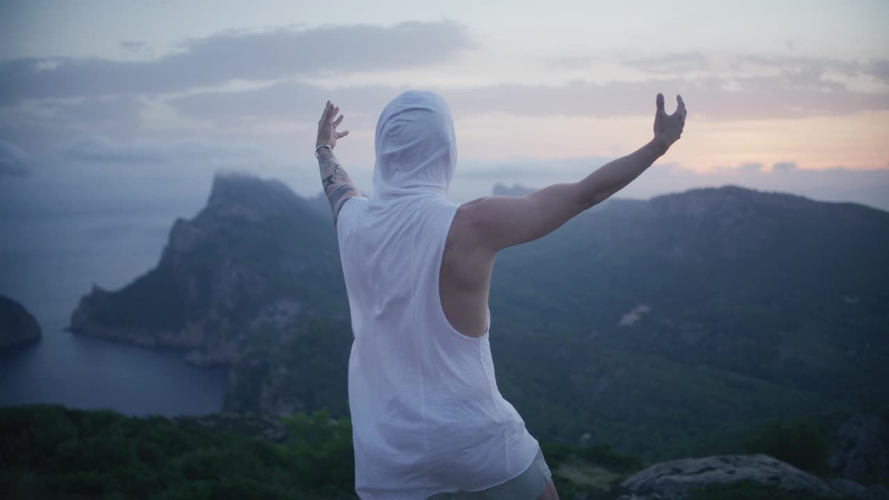 兜帽男站在世界之巅。站在山顶上欣赏美景并庆祝视频素材