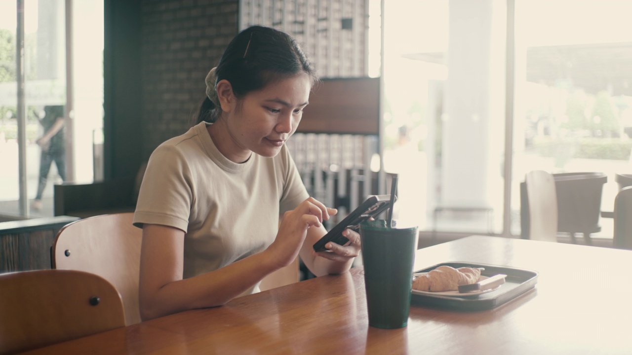 亚洲妇女在室内咖啡馆使用手机。视频素材