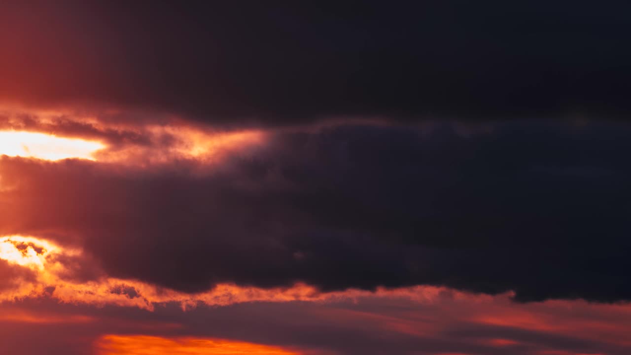 4k时间流逝日落天空背景。灿烂的太阳戏剧性的天空。黑暗的黄昏。橙色的阳光闪闪发光。饱和的橙红色。层云。阳光穿透云层。延时视频素材