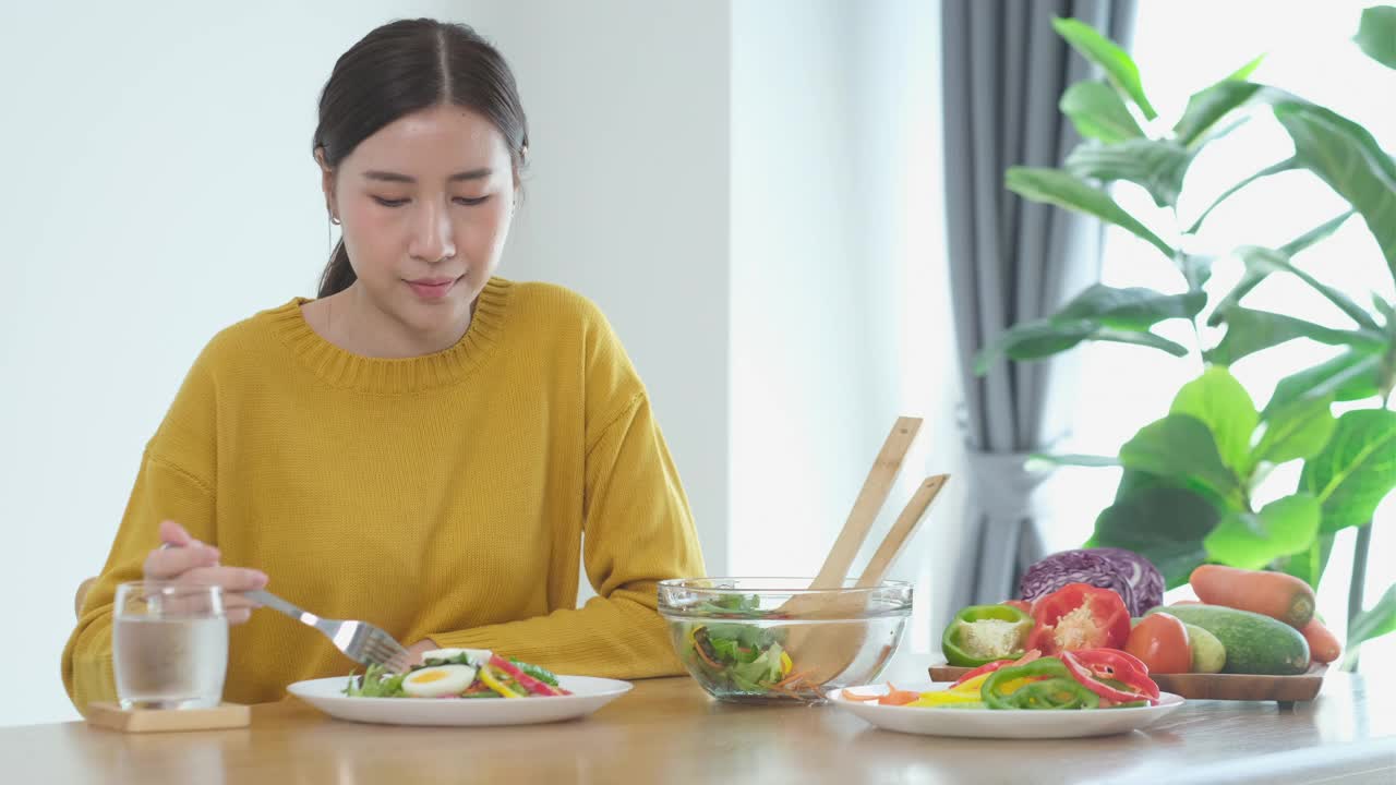 年轻的亚洲妇女在家里吃沙拉视频素材