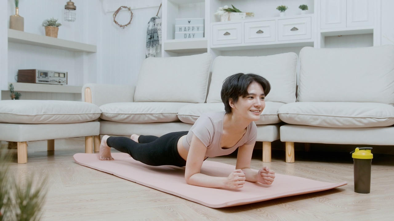 一名亚洲年轻女子在健身垫上锻炼，在家锻炼视频素材