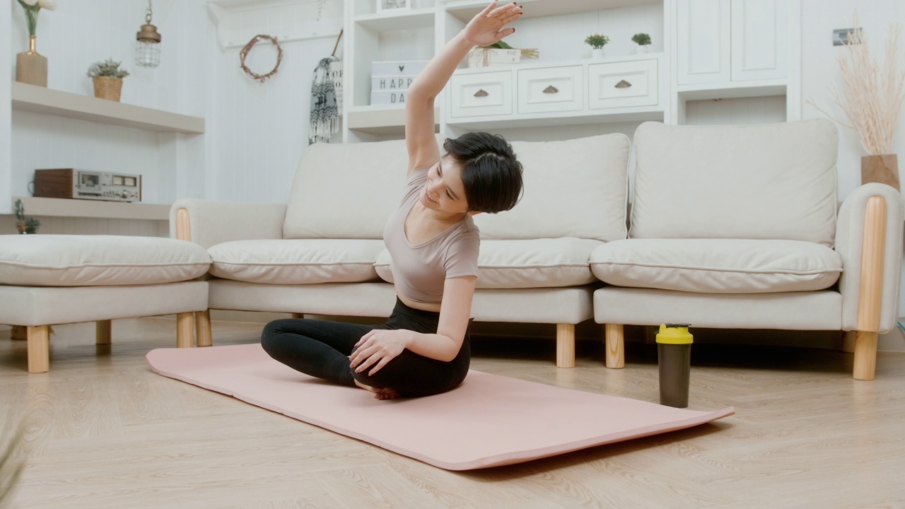 一名亚洲年轻女子在健身垫上锻炼，在家锻炼视频素材