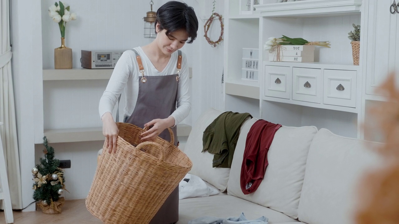 一个亚洲年轻女管家把乱七八糟的脏衣服放进篮子里清洗视频素材