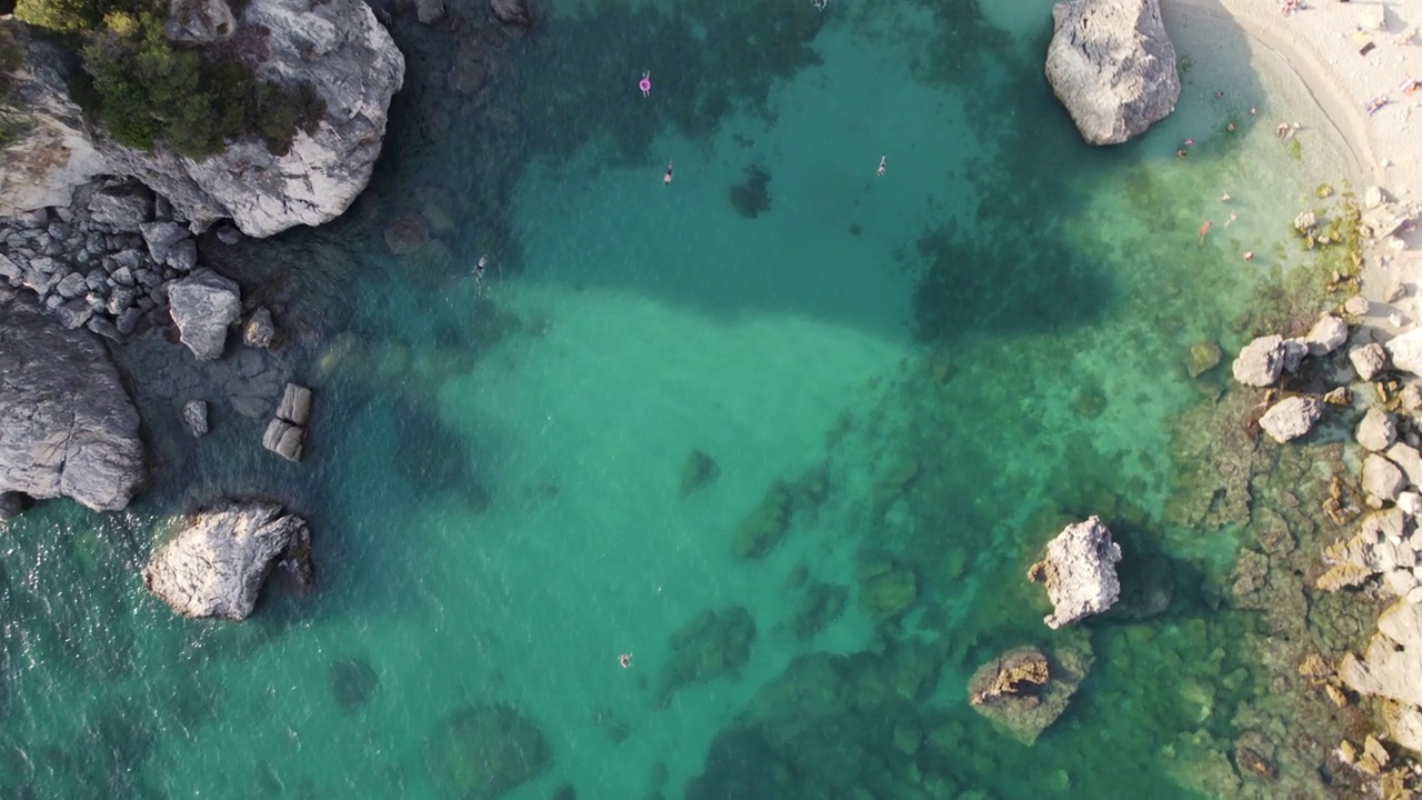 田园诗般的水晶清澈的蓝色海水与爱奥尼亚海岩石海岸;开销空中视频下载