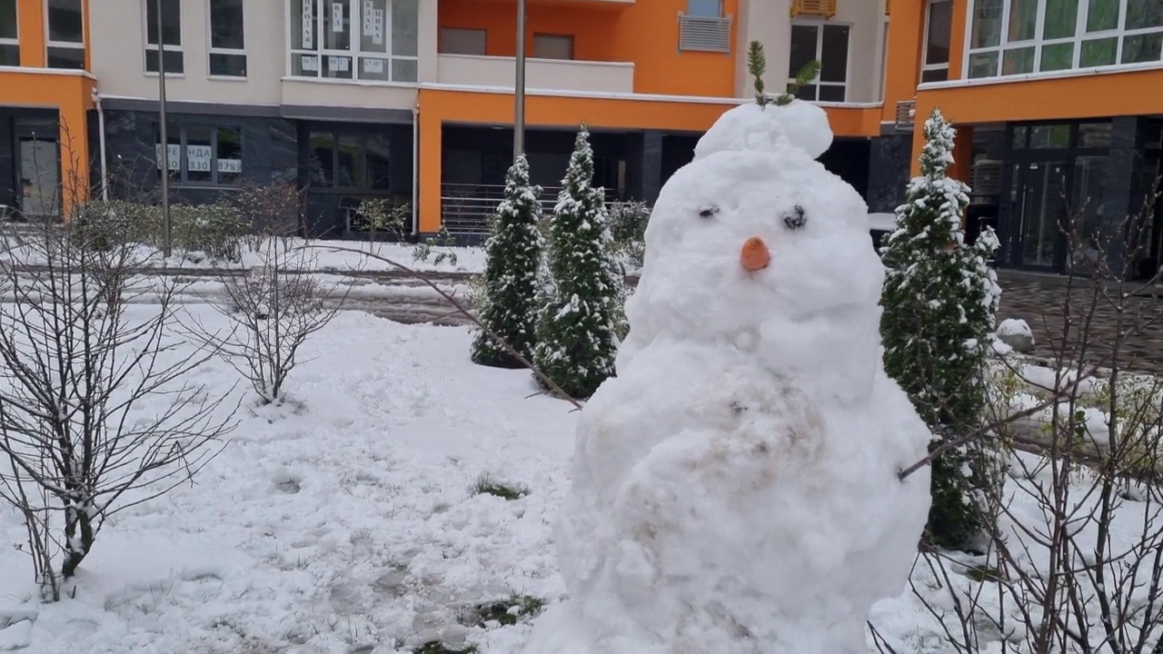 胡萝卜鼻子的白色雪人，用雪做的，冬天在住宅公寓的后院堆雪人。圣诞假期准备视频素材