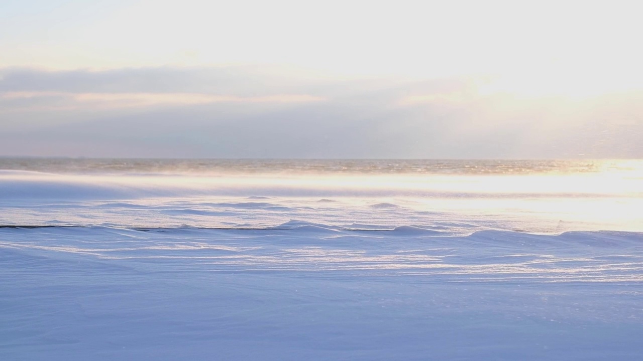 在海滩上日落的时候，海滩上的雪从风中蔓延开来视频素材