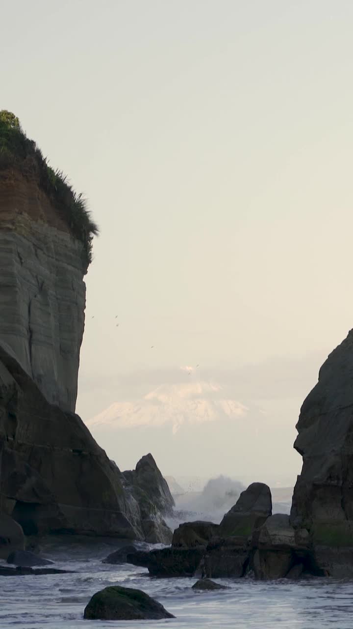 落日时分，海滩上满是岩层，后面是雪峰山。三姐妹和后面的塔拉纳基山视频素材