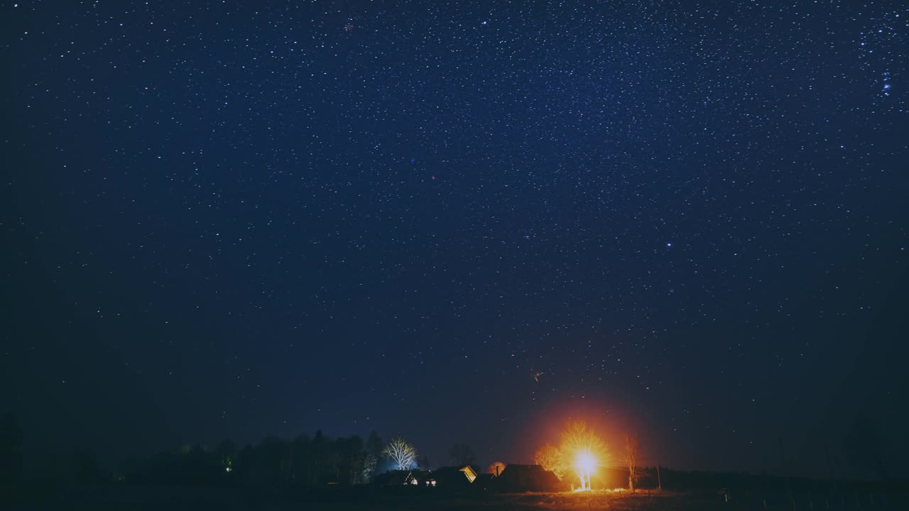 4k时间间隔夜星空上方的村庄。自然天空背景的乡村乡村景观。流星划过深蓝色的天空。大曝光。时间流逝，时间流逝，时间流逝视频素材