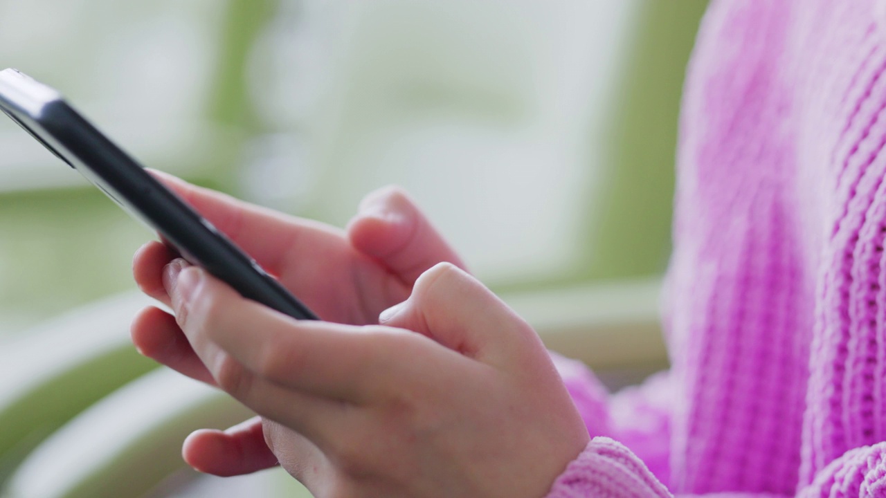 穿着鲜艳毛衣的少女在智能手机上与朋友在线聊天视频素材