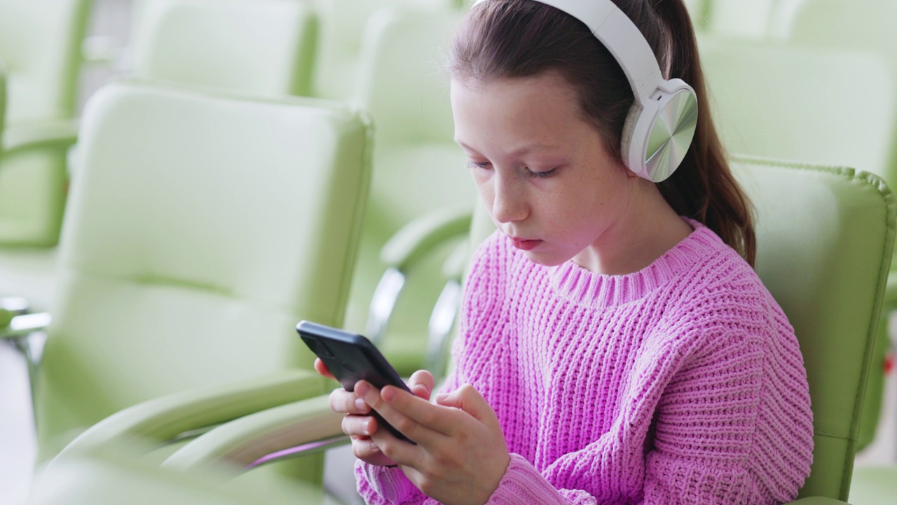 穿着鲜艳毛衣的少女在智能手机上与朋友在线聊天视频素材