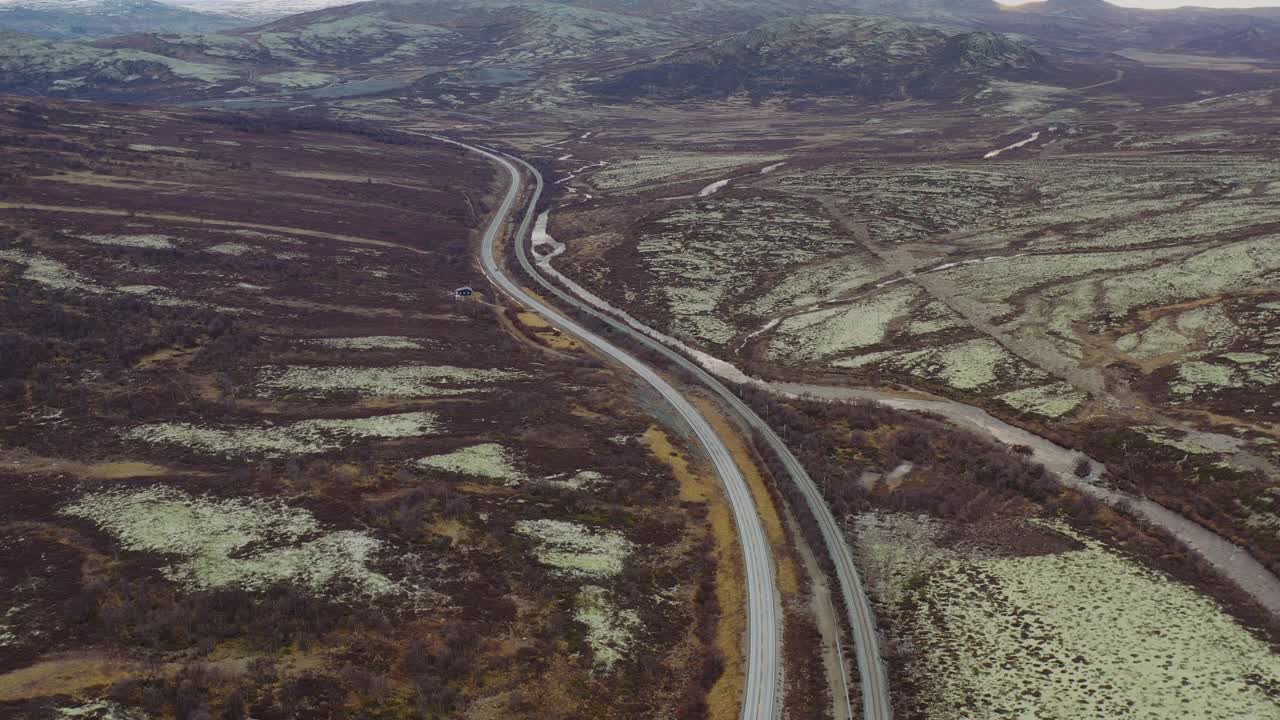 在挪威苔原上，汽车行驶在风景优美的弯曲山区公路上的鸟瞰图视频素材