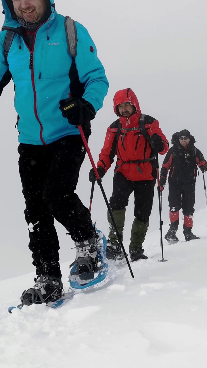 背包和雪鞋的徒步旅行者在冬季徒步旅行中行走。视频素材