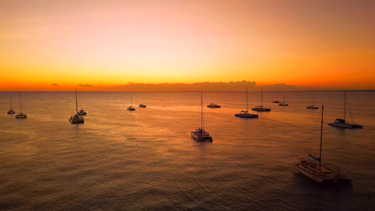 航拍在令人惊叹的粉色夕阳下停泊的旅游游艇和双体船的剪影。美丽的夜晚，平静的大海视频素材