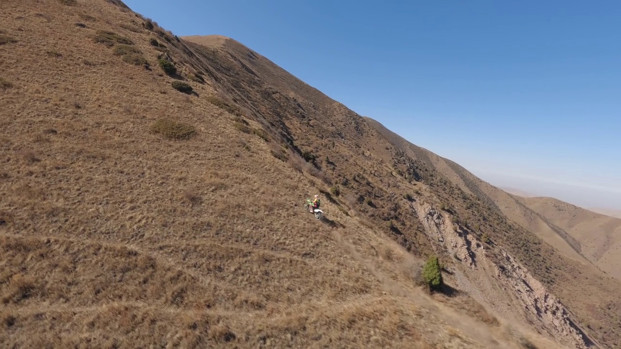 动态速度比赛山地摩托车运动男子骑上斜坡到山顶在阳光明媚的天空鸟瞰图视频素材