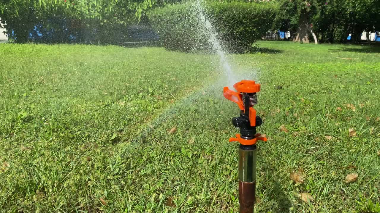 自动草坪洒水器，洒水器的水珠洒在绿油油的草坪上视频素材