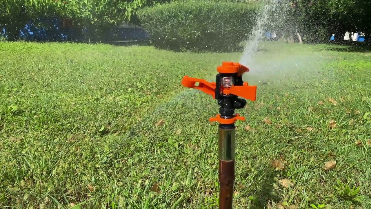 自动草坪洒水器，洒水器的水珠洒在绿油油的草坪上视频素材