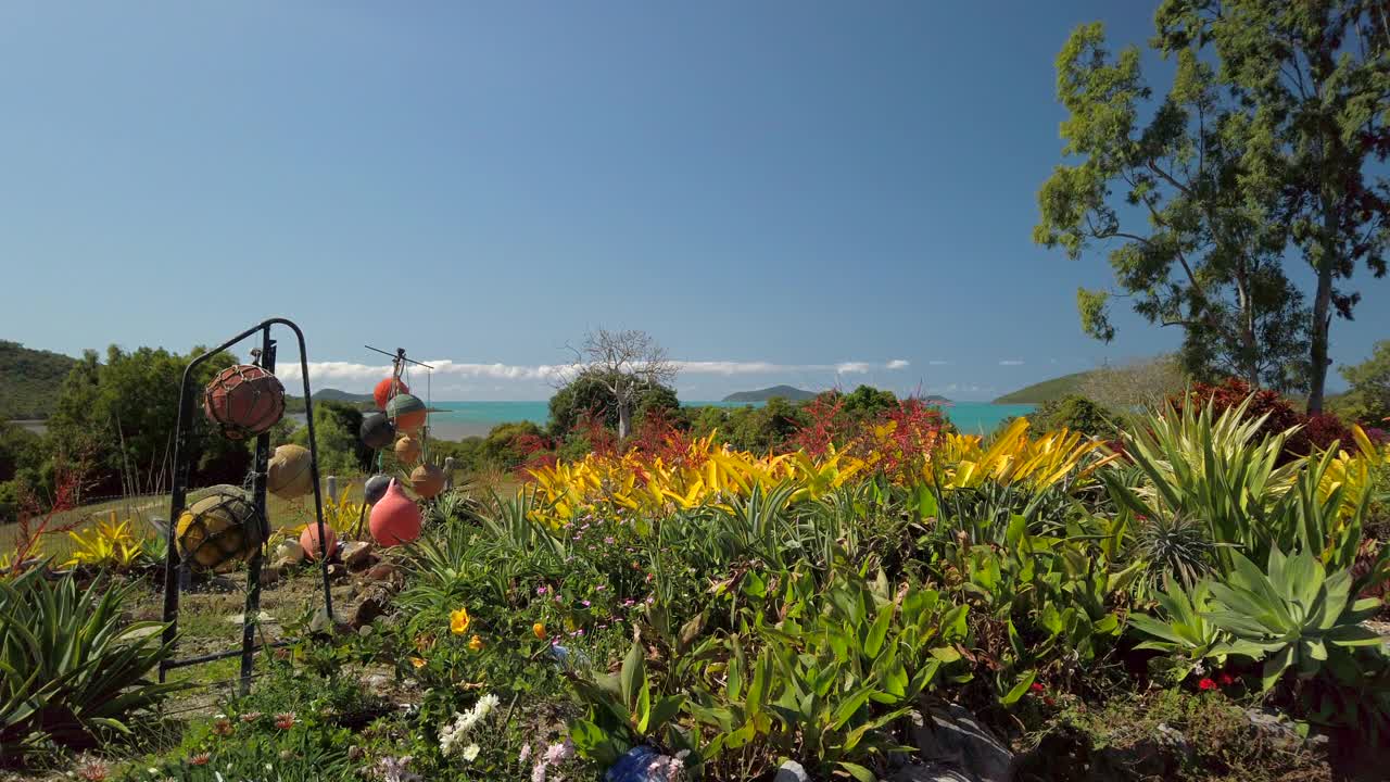 一个美丽的花园，郁郁葱葱的绿草俯瞰着湛蓝大海中的热带岛屿。视频素材