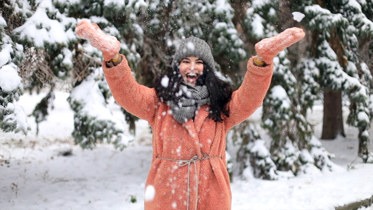 快乐的年轻女子在寒假里玩雪，一个女子把白色的、松散的雪抛向空中。视频素材