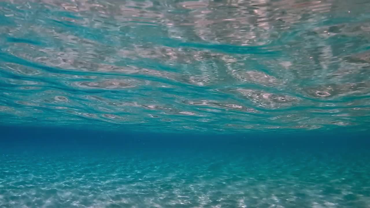 令人难以置信的水下结晶蓝绿色热带海水与涟漪表面和反射在海底与蓝色背景视频素材