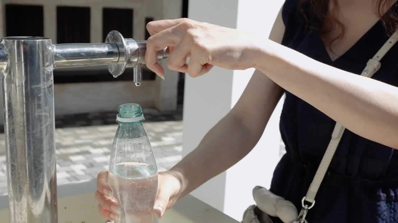 特写手年轻女子倒矿泉水瓶在源头视频素材