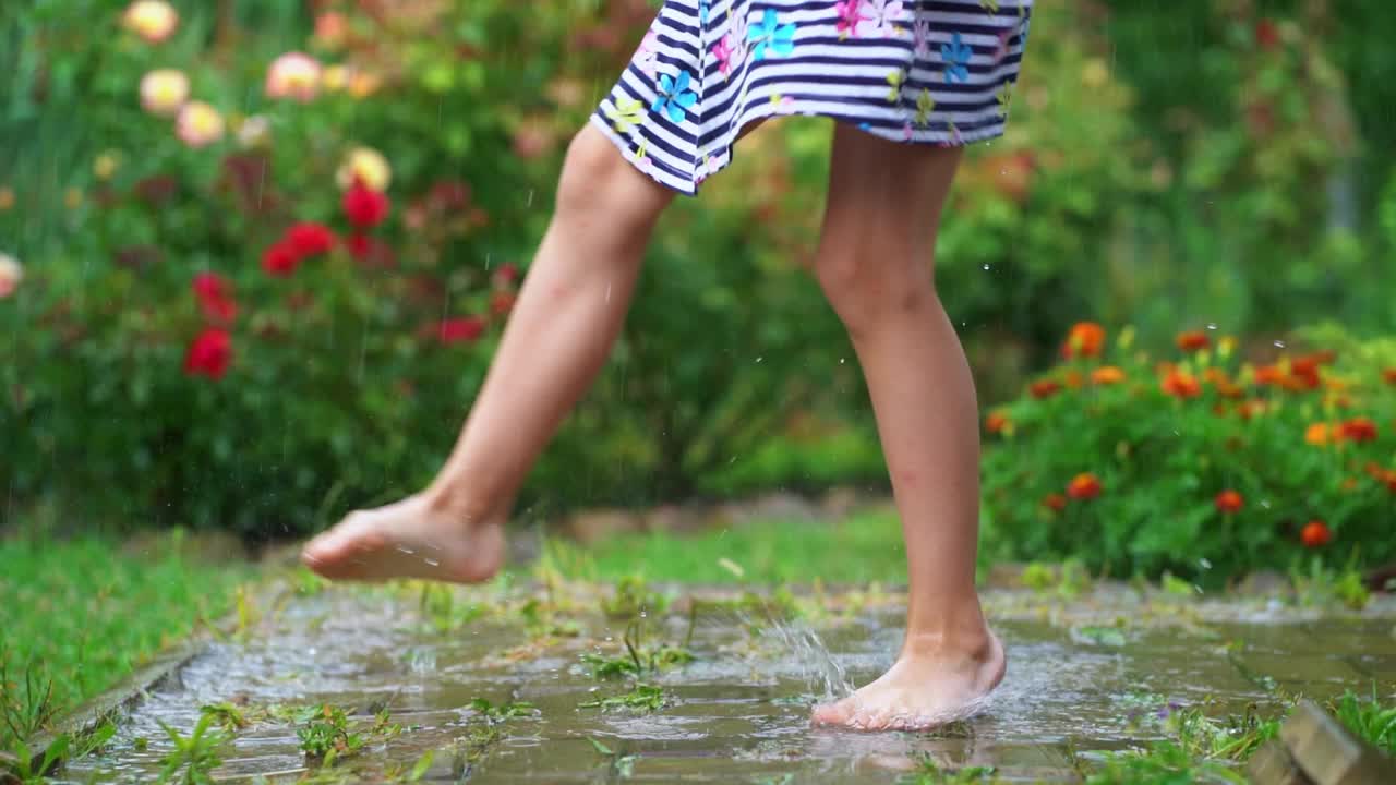 快乐的童年。在温暖的夏日，赤脚女孩在雨下跳舞视频素材