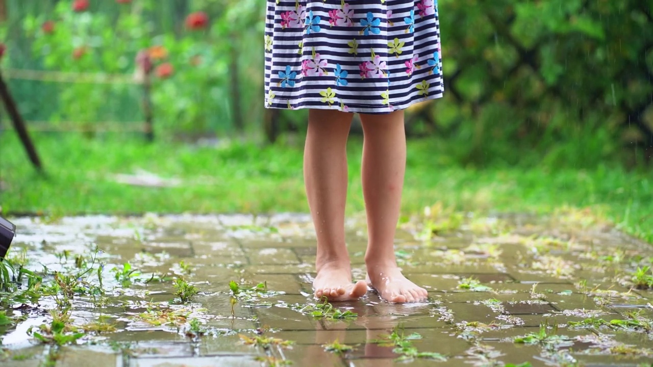 乡村生活，童年。在温暖的夏日，赤脚女孩站在雨下视频素材