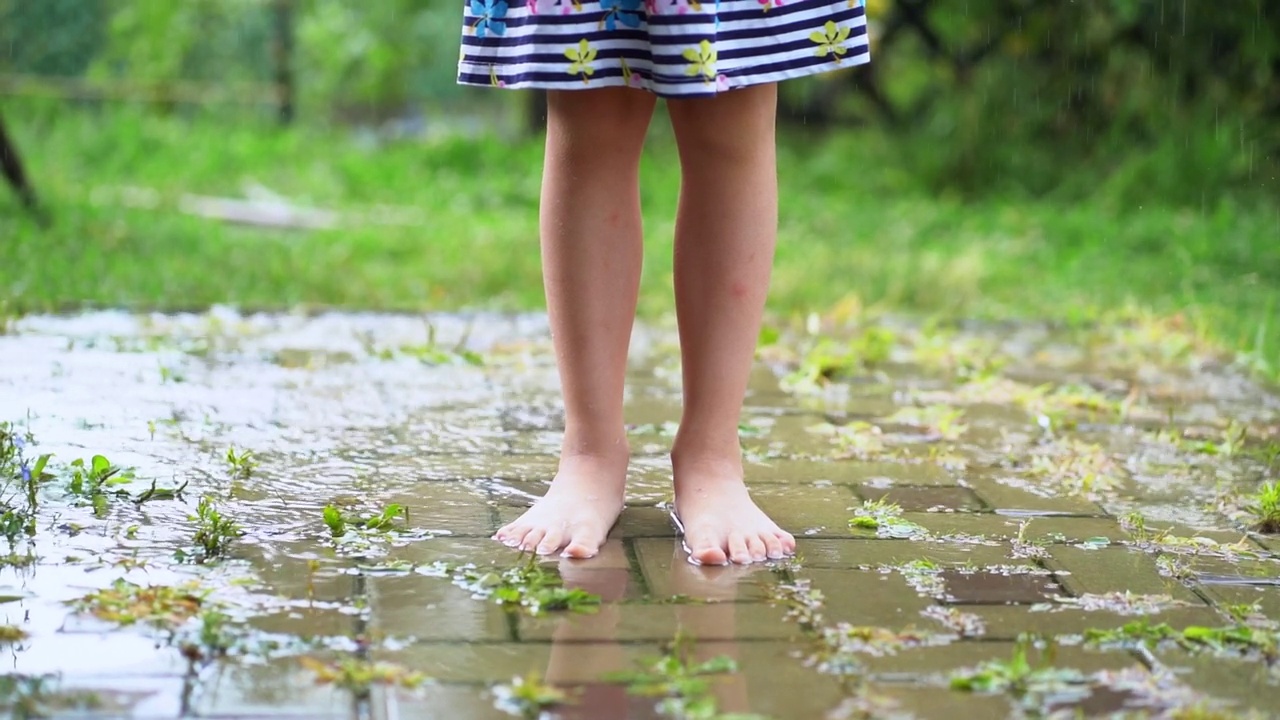 在温暖的夏日，赤脚女孩站在雨下视频素材