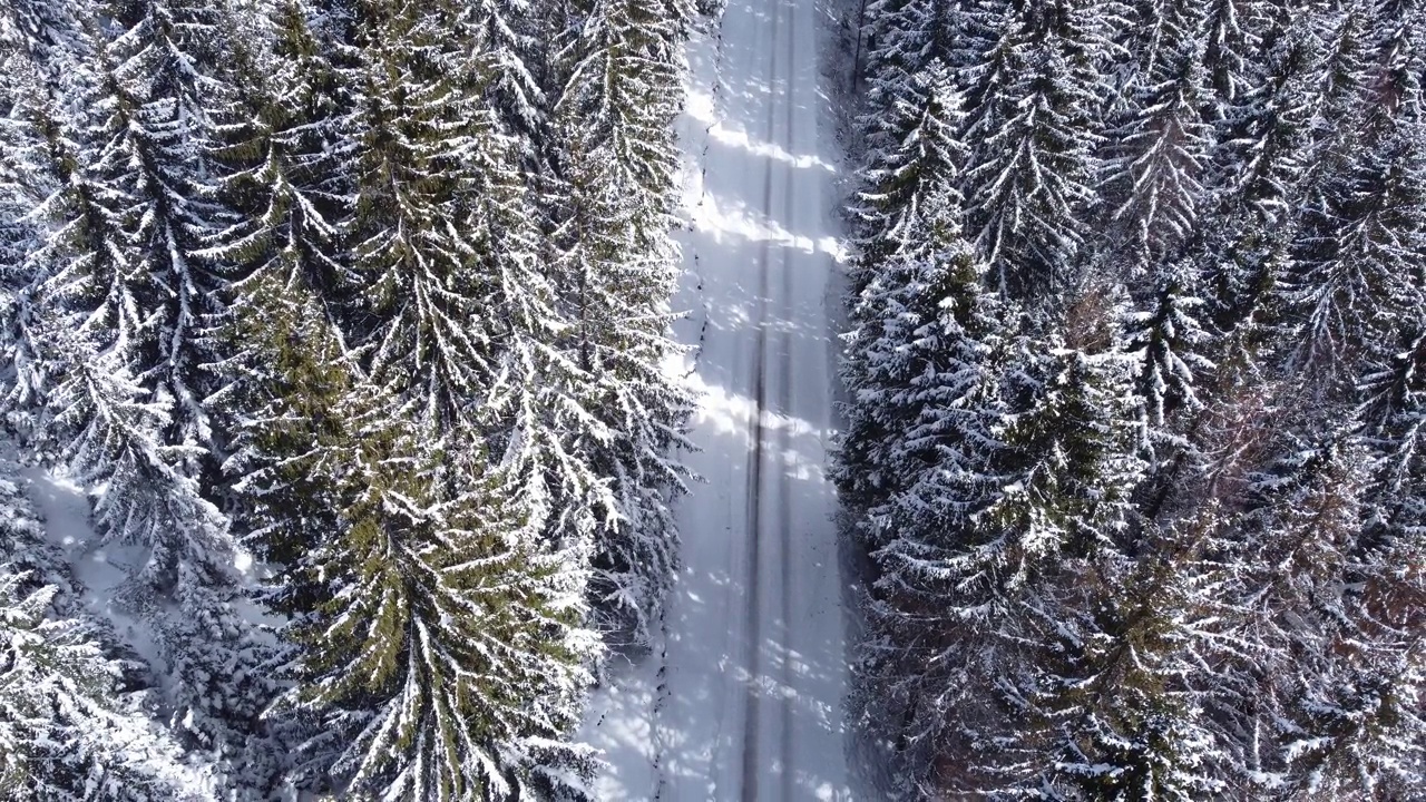 冬季山路上行驶的汽车。鸟瞰白雪皑皑的森林与道路。视频下载